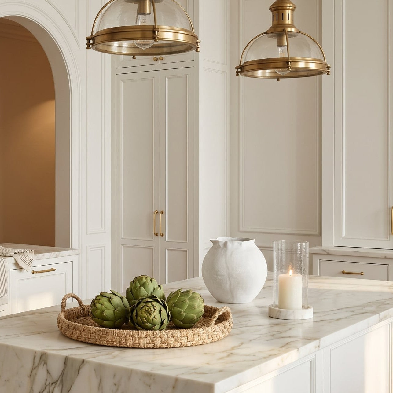 Modern kitchen with marble island, gold fixtures, and decorative elements.