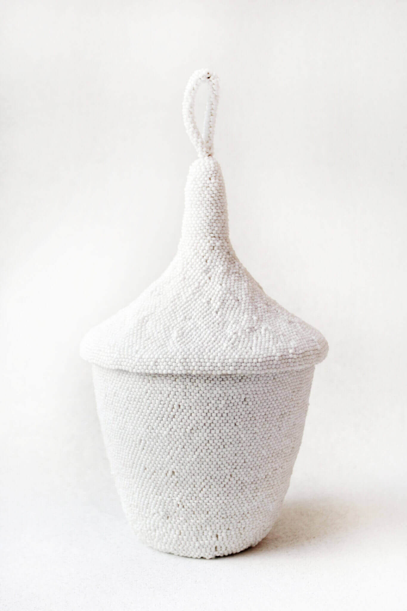White woven basket with a lid on a white background