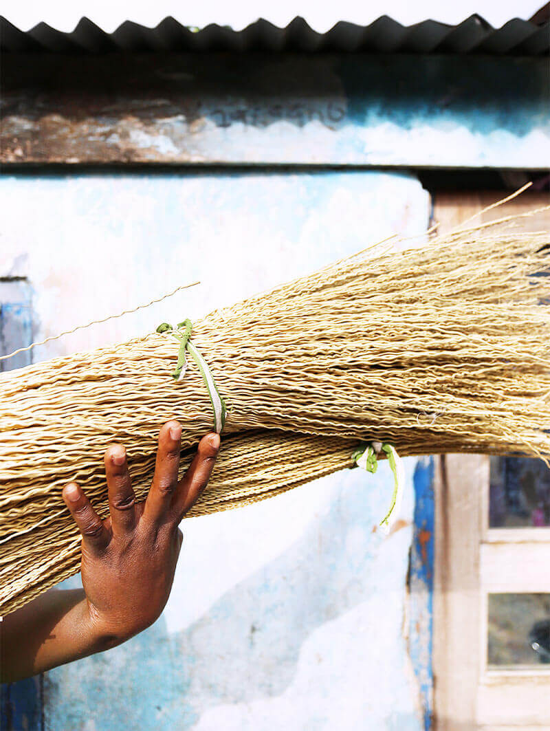 Hand holding a broom against a corrugated metal wall