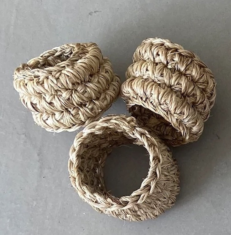 Three woven napkin rings made of natural material on a gray background