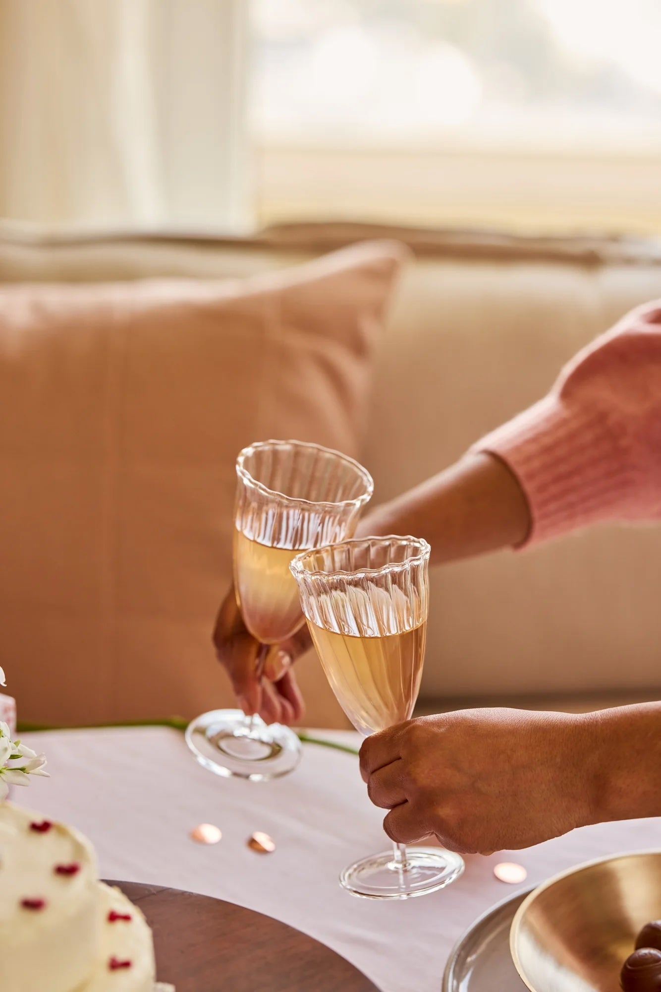 Two people holding glasses of champagne in a cozy indoor setting.