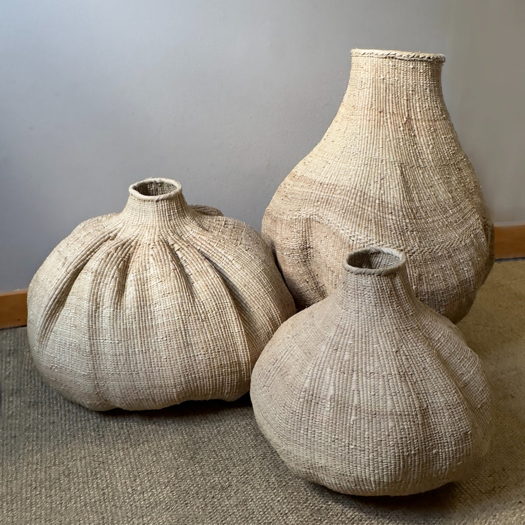 Handwoven natural belly basket vase with a sculptural rounded silhouette, artisan-crafted from woven natural fibers for displaying dried branches, pampas grass, and modern organic home décor.
