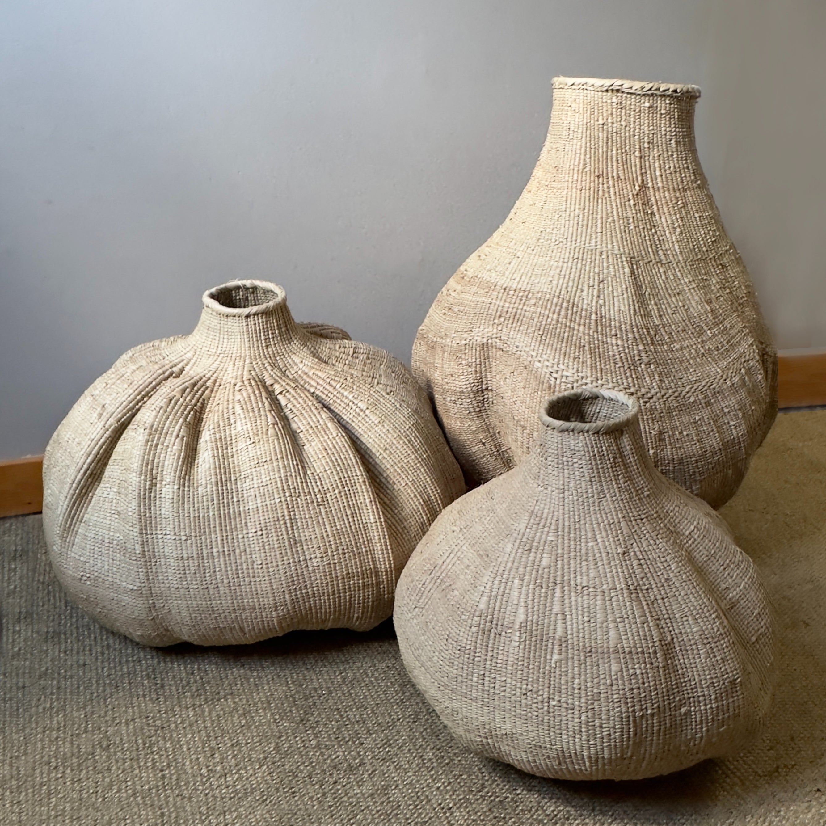 Handwoven natural belly basket vase with a sculptural rounded silhouette, artisan-crafted from woven natural fibers for displaying dried branches, pampas grass, and modern organic home décor.