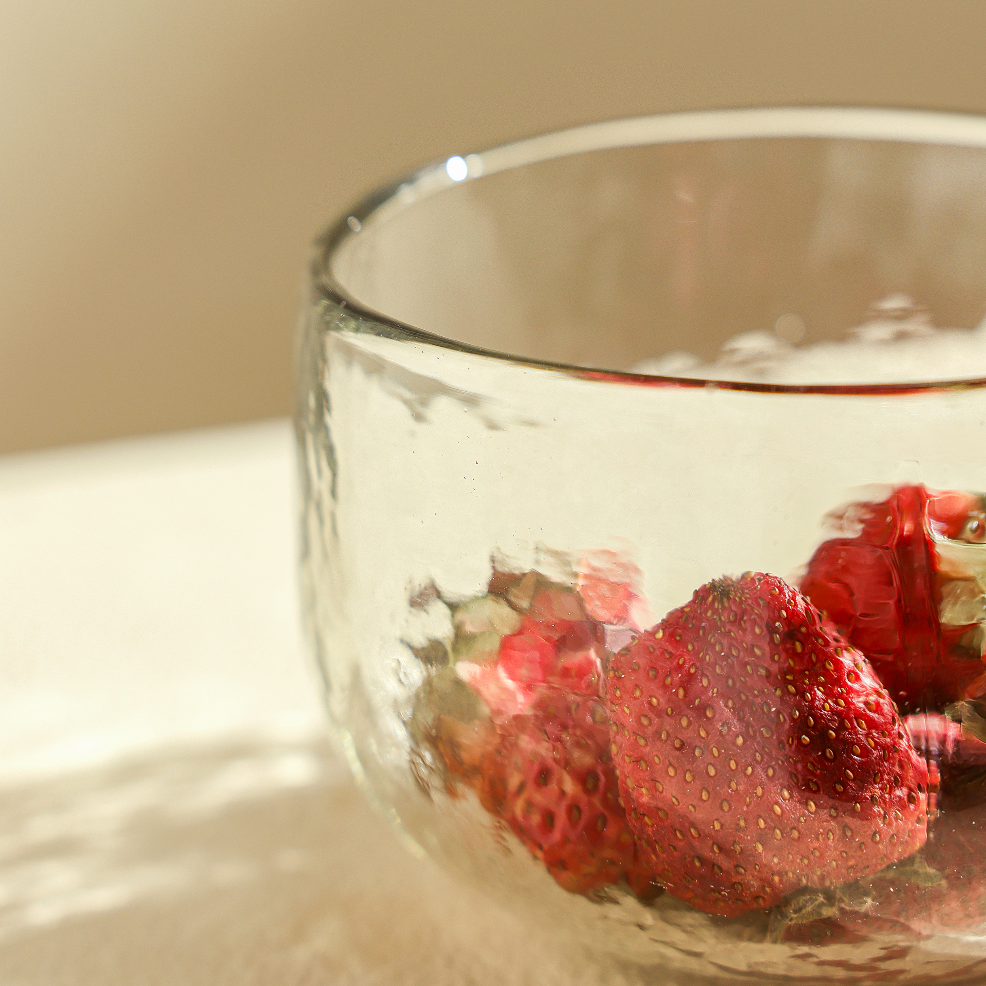 Clear glass bowl with strawberries on a light surface