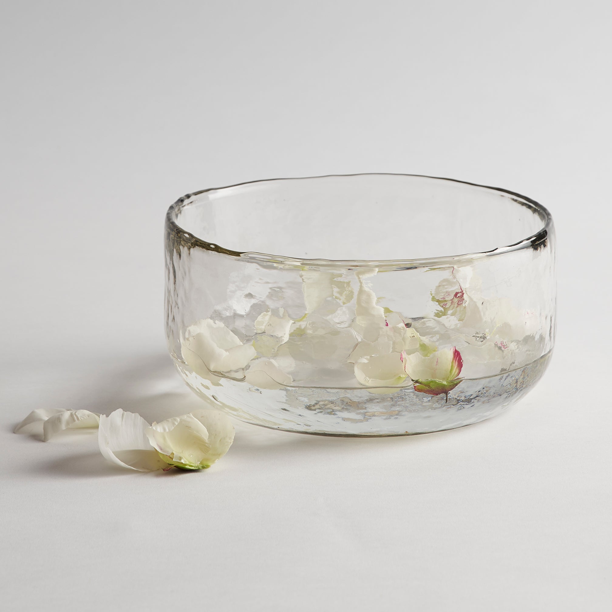 Clear glass bowl with white flowers on a light gray background