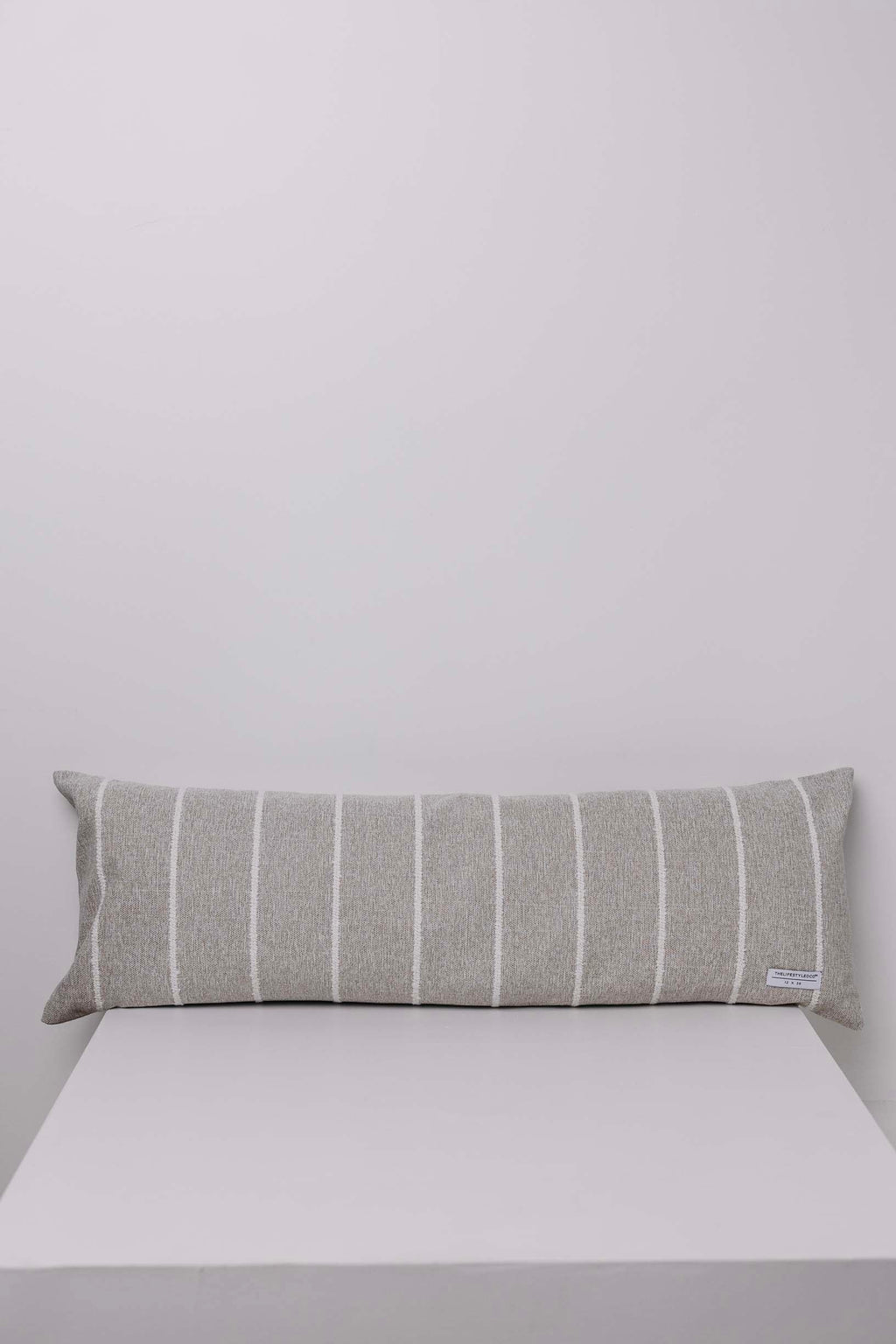 Gray striped pillow on a white surface with a light gray background
