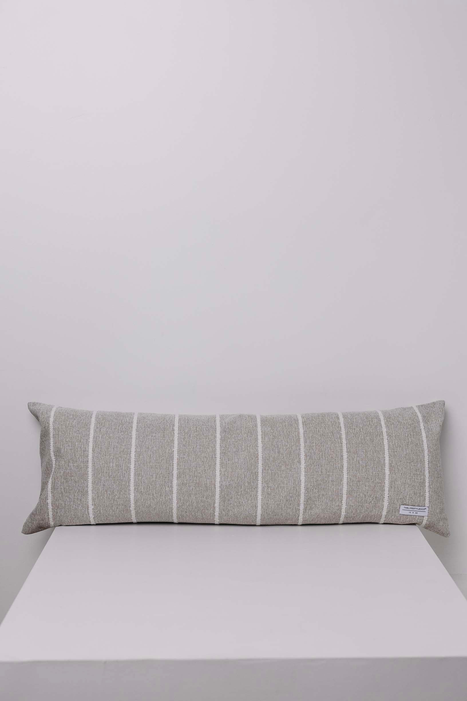 Gray striped pillow on a white surface with a light gray background