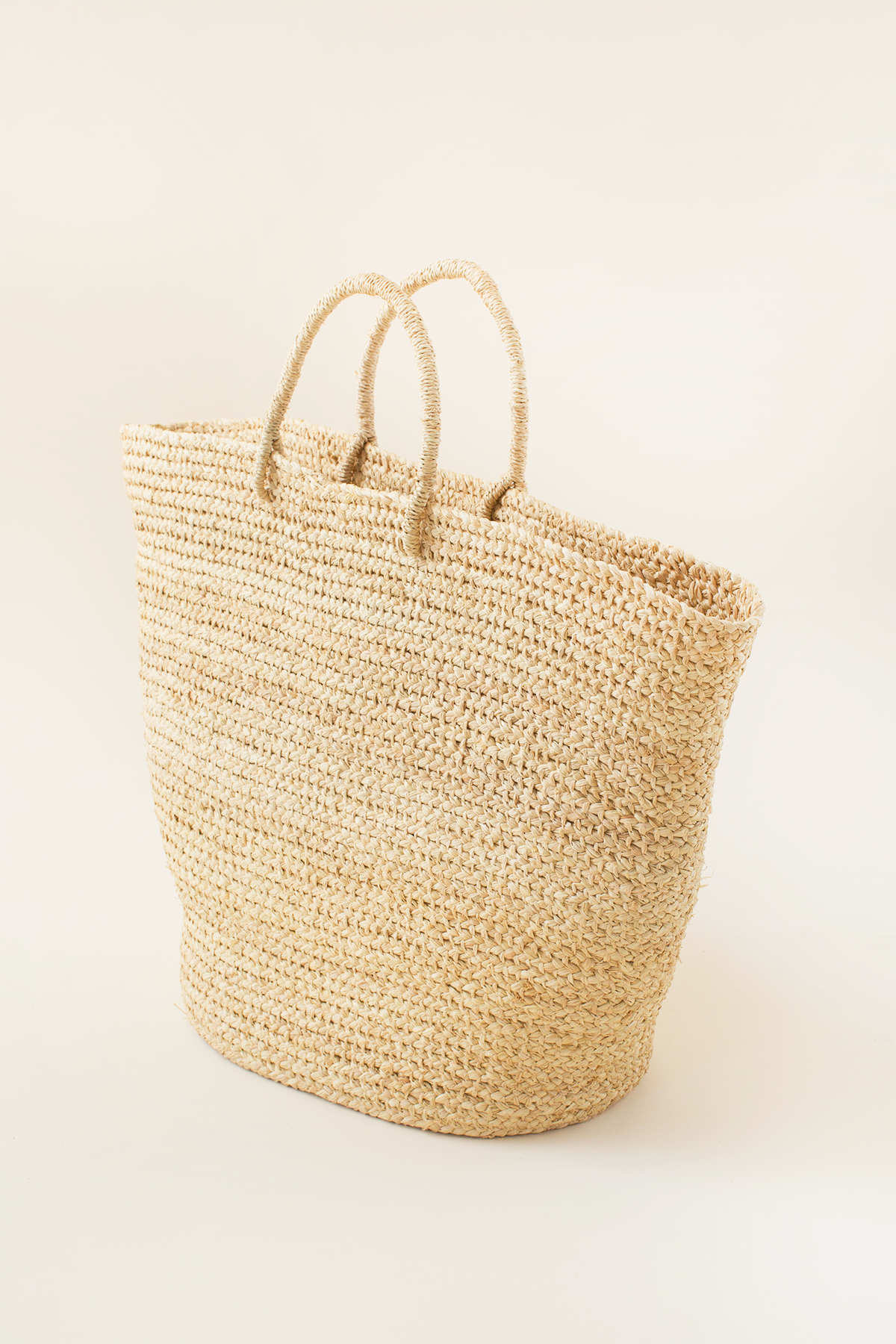 Woven straw tote bag on a light beige background