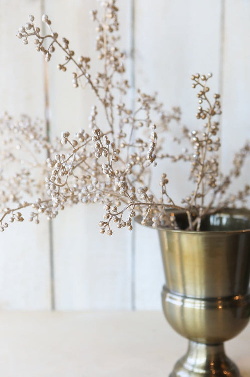 Decorative vase with dried flowers against a light wooden panel background