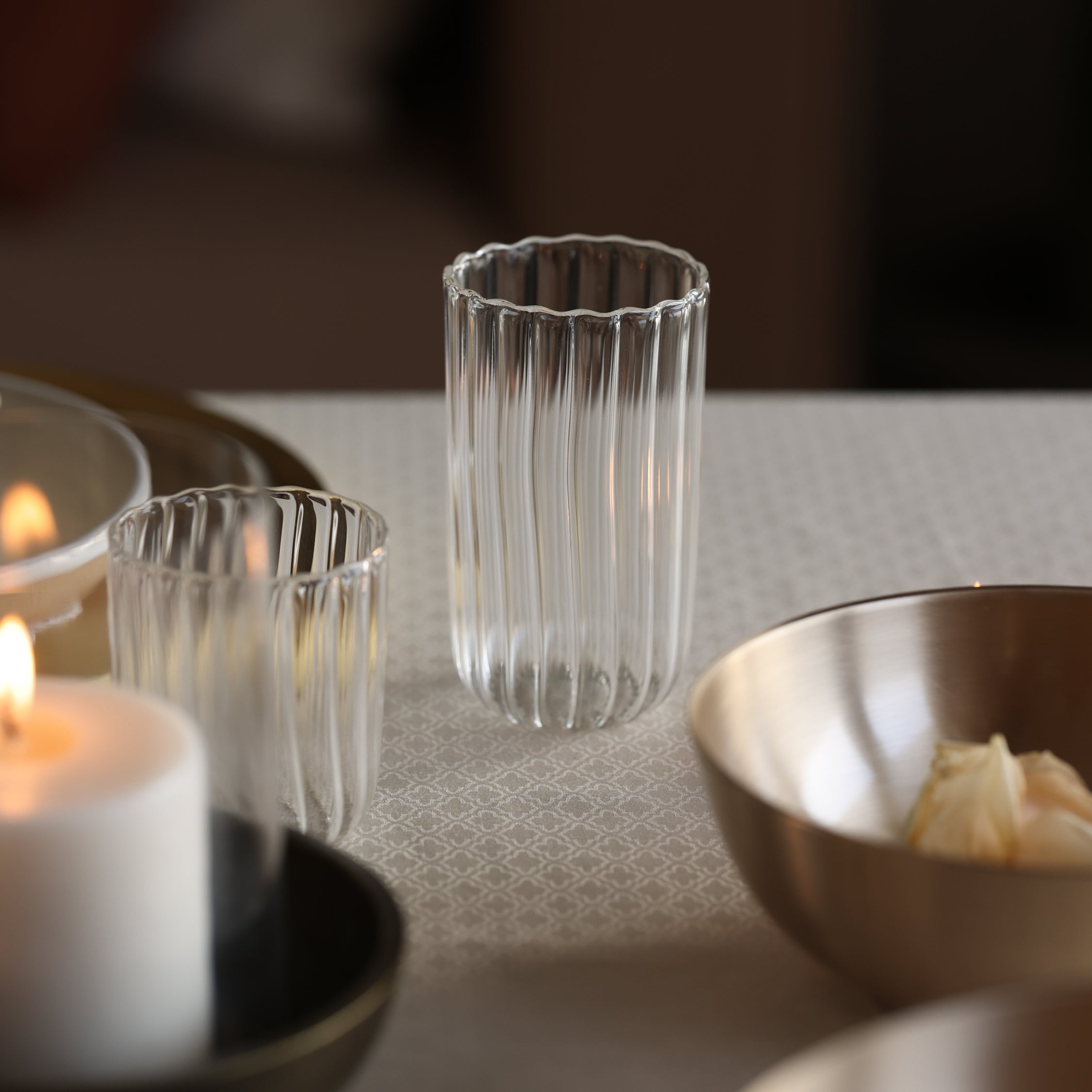 Clear glass with a candle and bowl on a textured surface