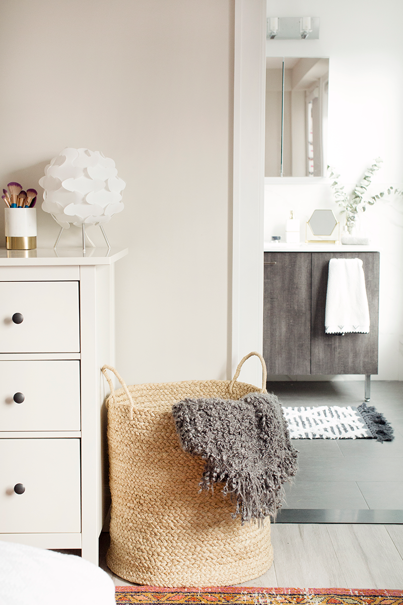 Bathroom interior with a woven basket, towel, and vanity.