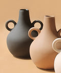 Three ceramic vases in black, beige, and white on a beige background
