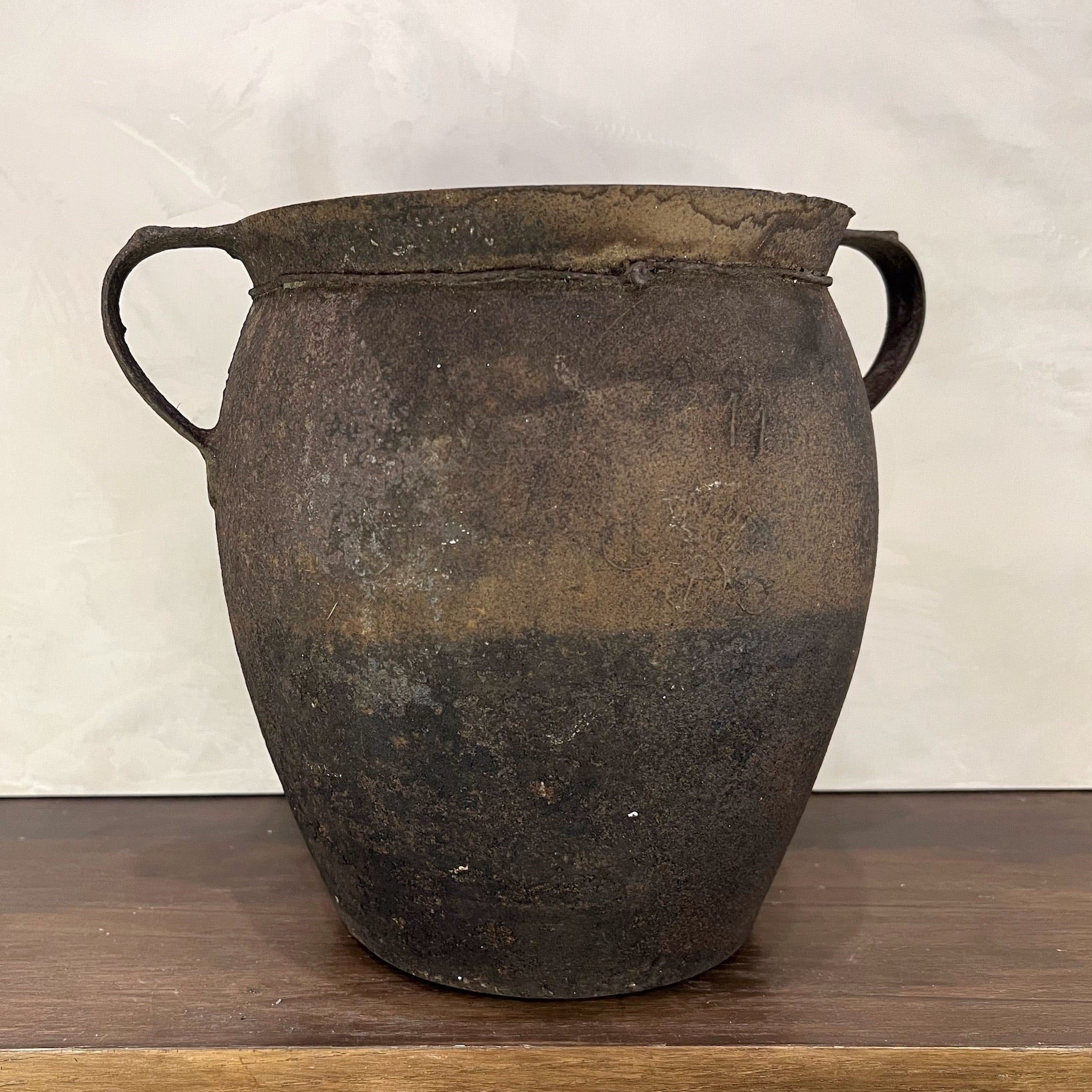 Vintage pot with handles on a wooden surface and white background