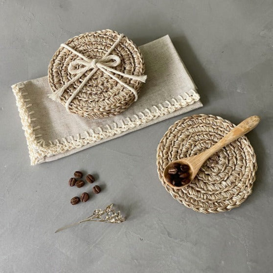 Set of handwoven round natural jute coasters featuring a braided design in warm beige tones. These artisan-crafted coasters add organic texture and timeless style to coffee tables, dining spaces, and neutral coastal, farmhouse, and European-inspired interiors.