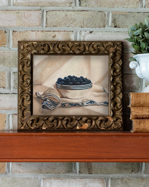 Blueberries in a striped bowl fine art print featuring ripe blueberries gathered in a cream ceramic bowl with blue stripes atop a patterned textile. Soft neutral tones, painterly brushstrokes, and classic still life composition create timeless wall art for kitchens, dining rooms, and European-inspired interiors.