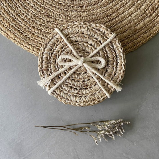 Woven coasters with a central bow on a gray surface