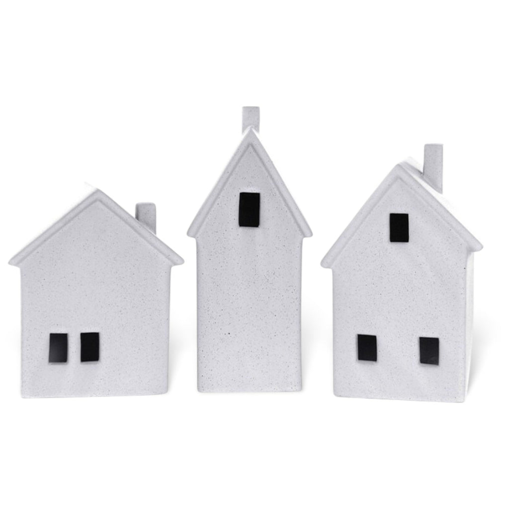 Three small white house-shaped ornaments with black window details, arranged side by side on a plain white background.
