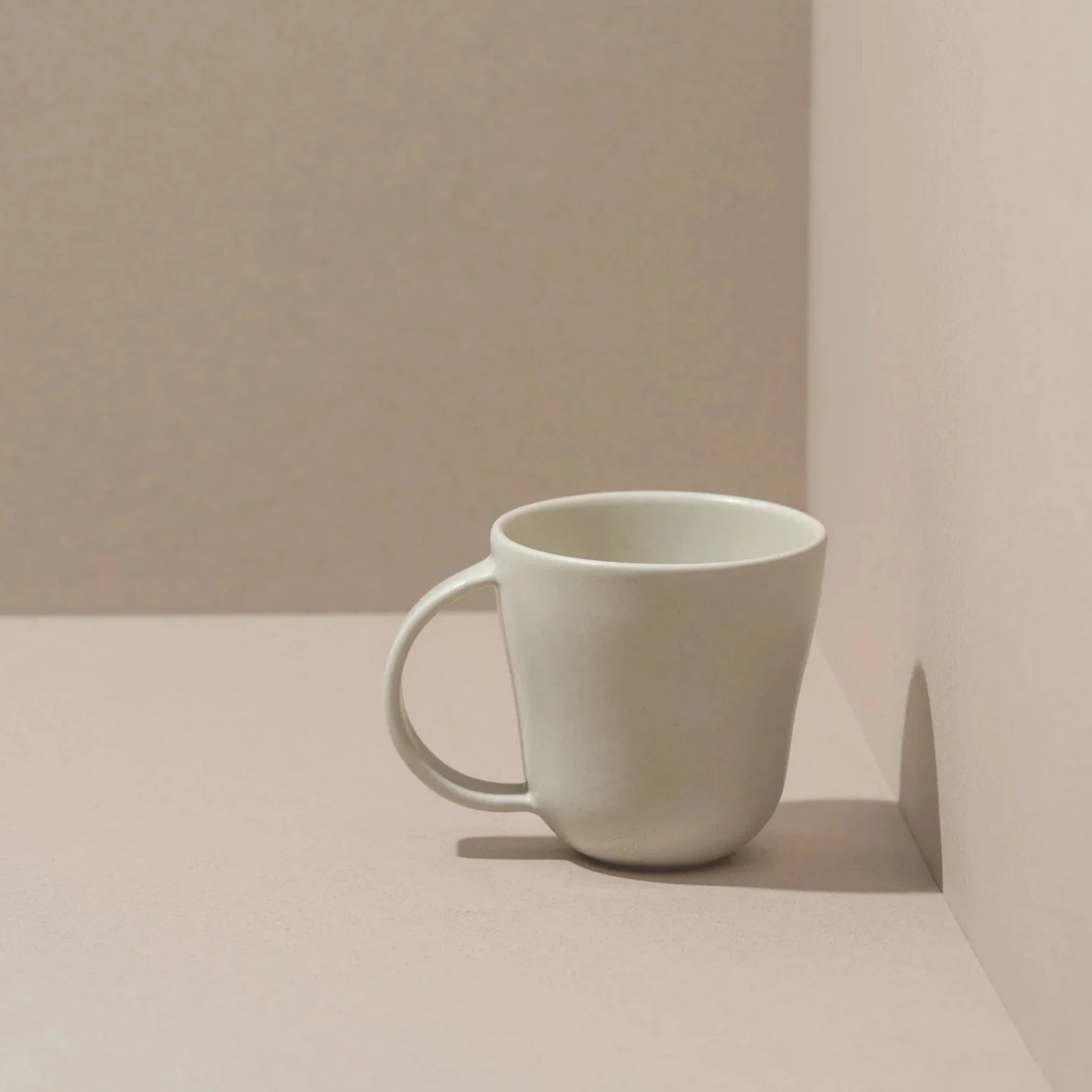 White ceramic mug on a beige surface with a neutral background