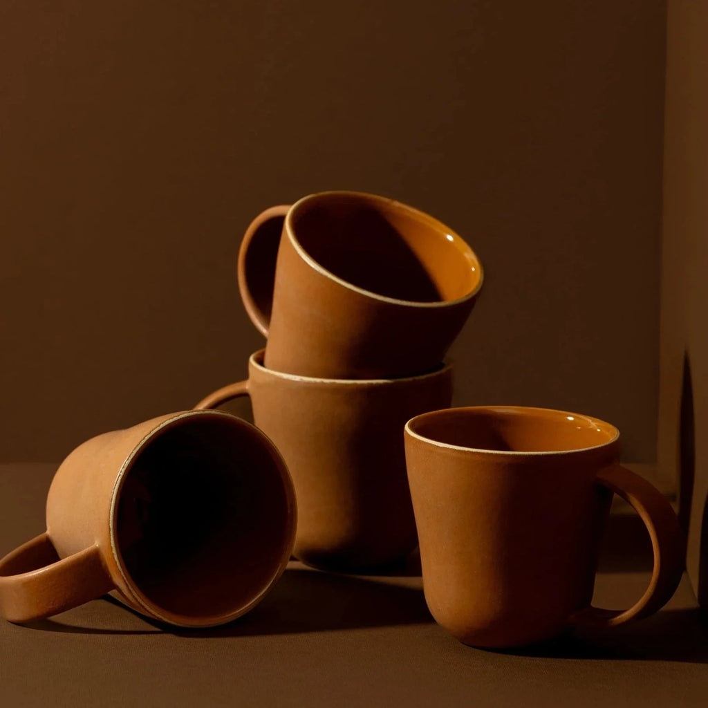 Stack of brown ceramic mugs on a brown background