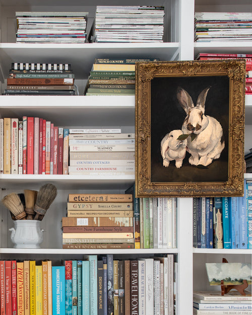 Bookshelf with books and a framed picture of two rabbits