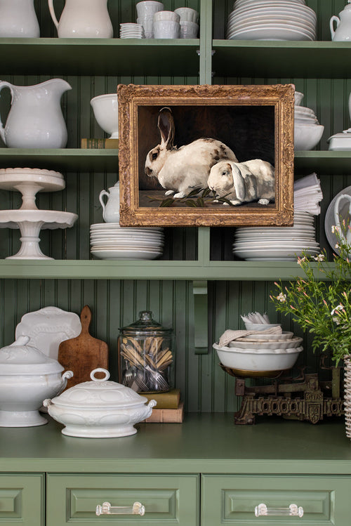 Decorative shelf with vintage-style rabbit print, white ceramic items, and green wall.