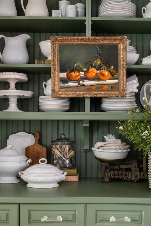 Decorative shelf with kitchenware, including a framed painting of pumpkins.