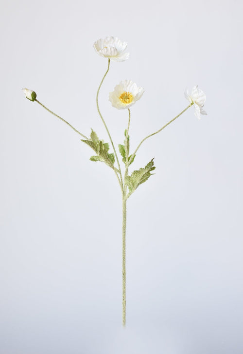 Artificial flower stem with white flowers on a light gray background