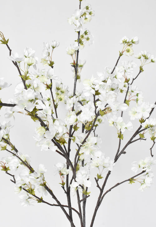 Artificial white cherry blossom branch on a light gray background