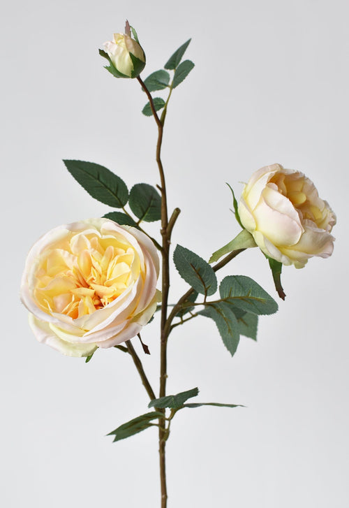 Artificial flower arrangement with yellow and pink roses on a light gray background