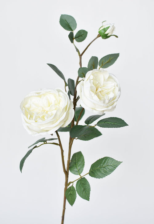 Artificial flower branch with white flowers and green leaves on a light gray background