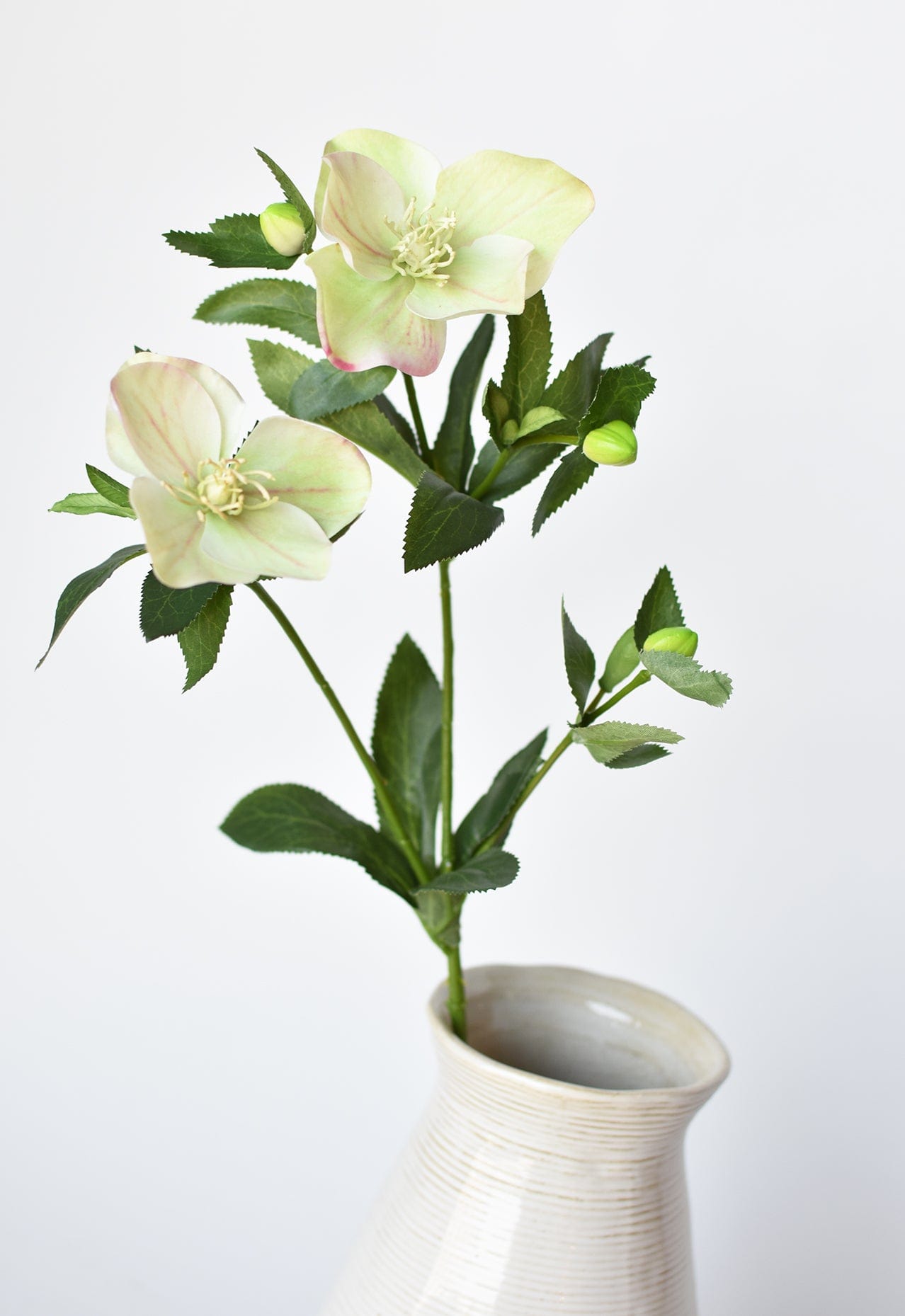 Artificial flowers in a white vase on a light gray background