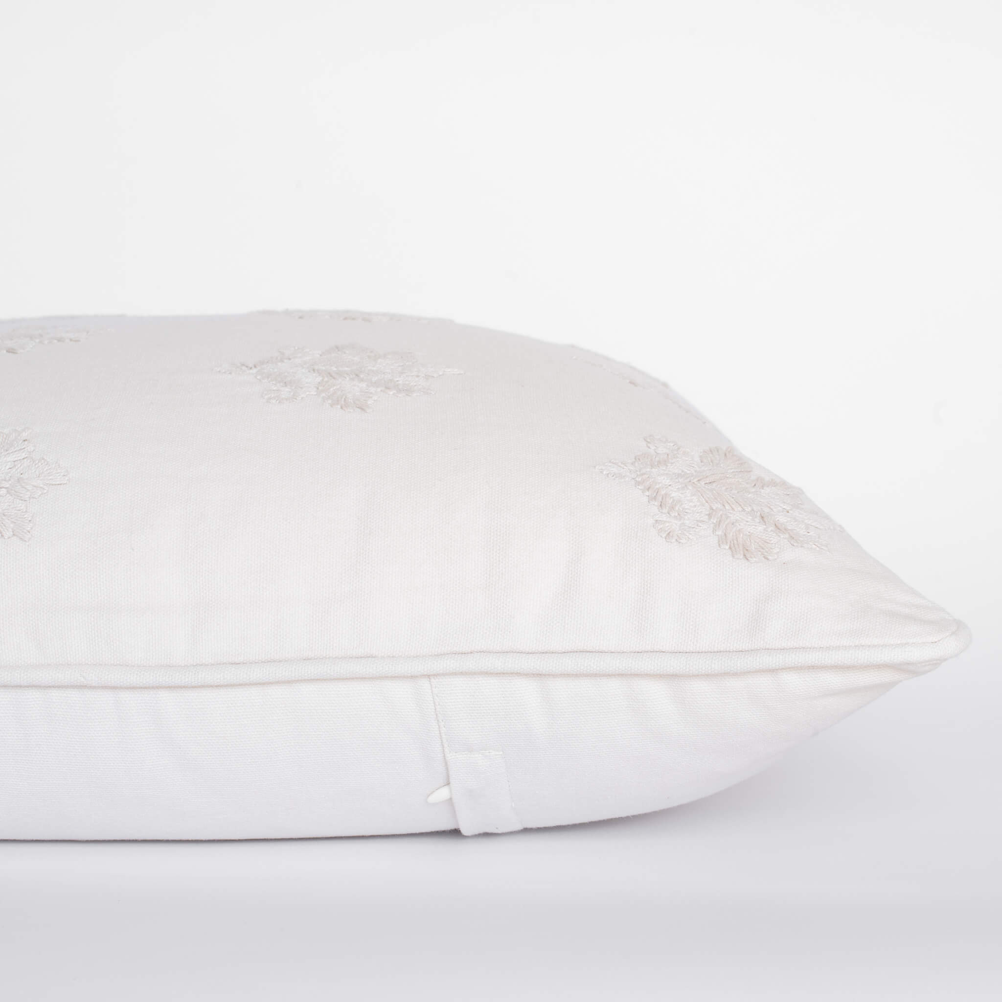 White pillow with lace trim on a white background