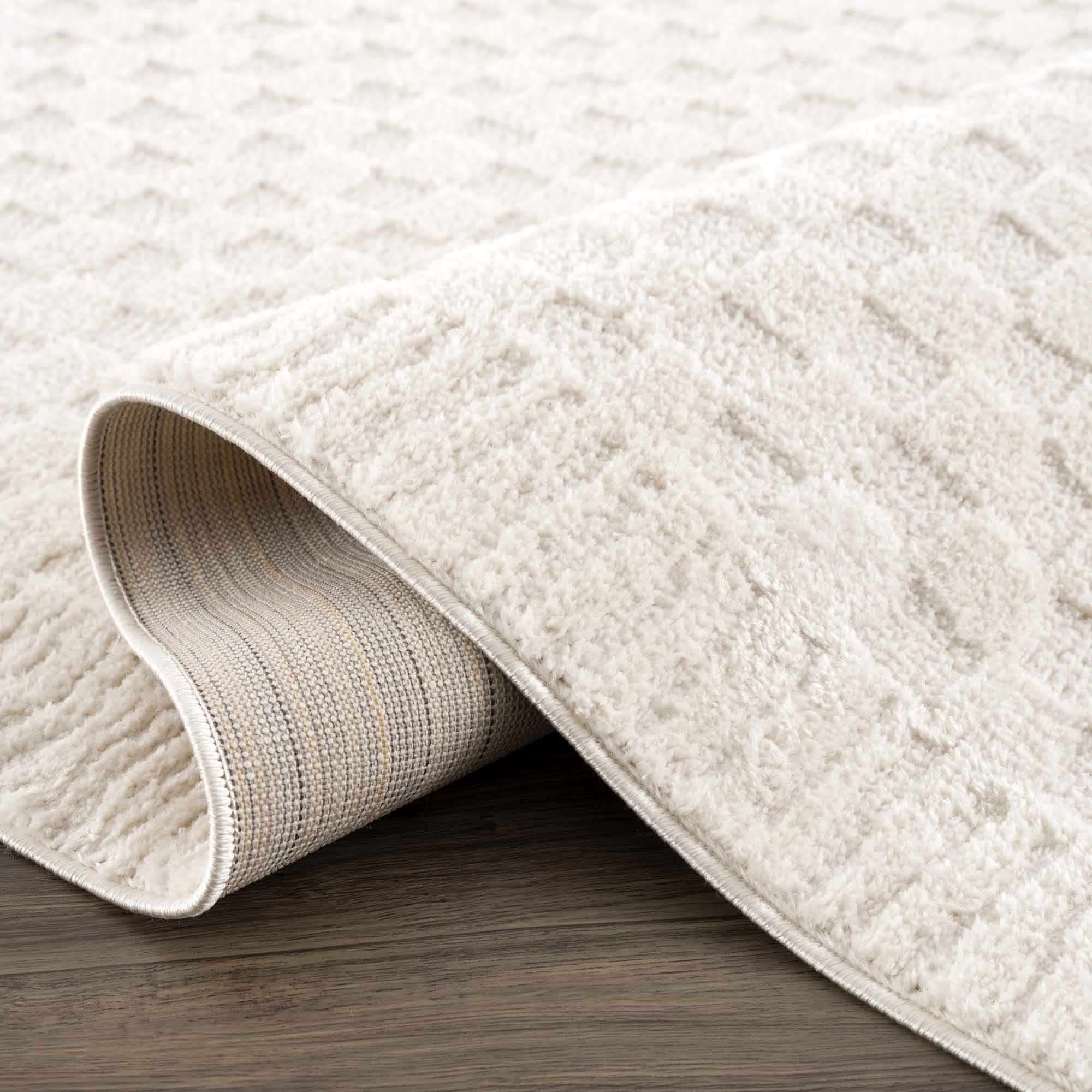 Textured beige rug on a wooden floor