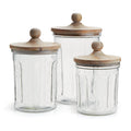Three glass jars with wooden lids on a white background