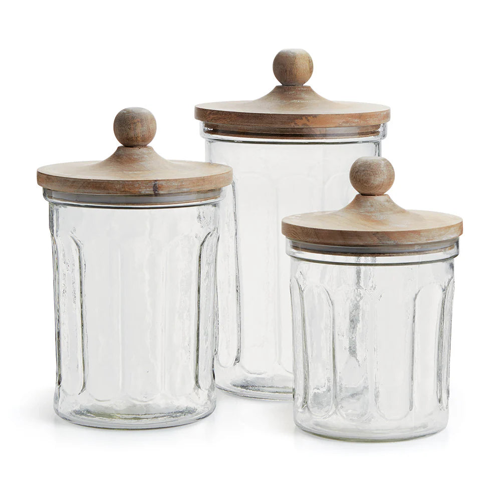 Three glass jars with wooden lids on a white background