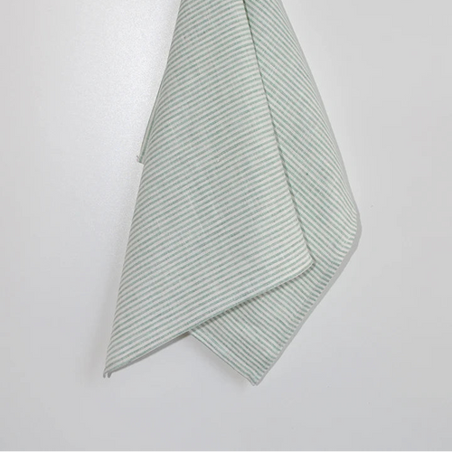 Green textured towel hanging on a wooden hook against a white background
