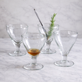 Set of clear glass cocktail glasses on a marble surface with a light gray background