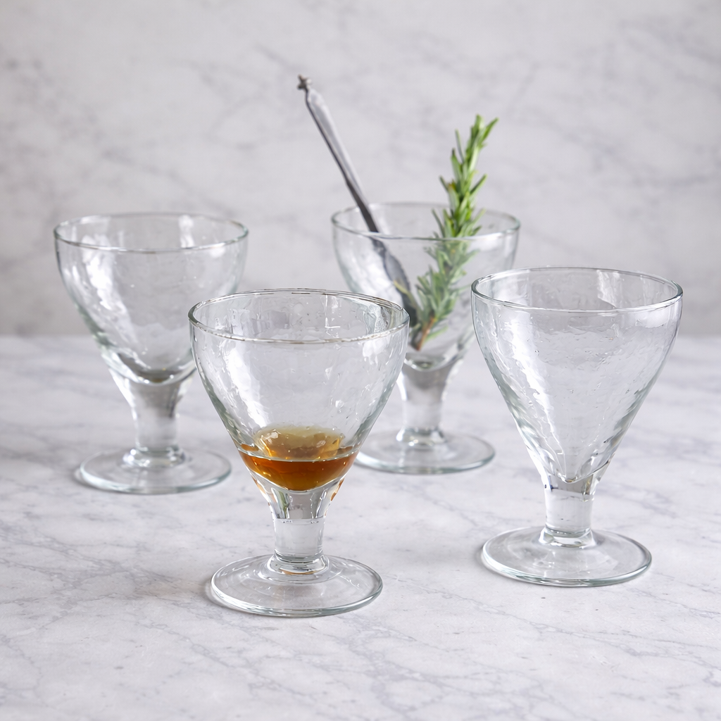 Set of clear glass cocktail glasses on a marble surface with a light gray background