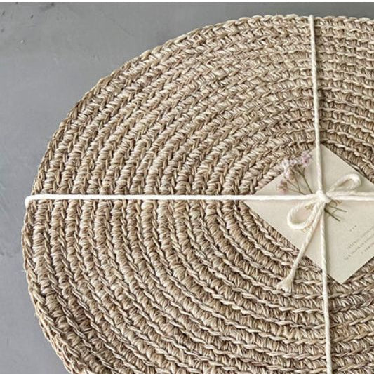 Handwoven round placemats in a soft natural beige tone featuring tightly braided woven texture and an organic neutral finish. Artisan-inspired woven table placemats styled with twine wrapping, perfect for European-inspired dining tables, layered tabletop decor, and timeless everyday entertaining.