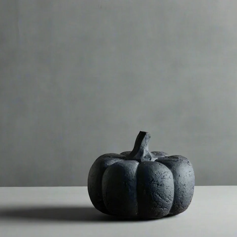 Black pumpkin-shaped object on a gray surface with a gray background