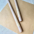 Two decorative pens with lace-like patterns on a beige surface.