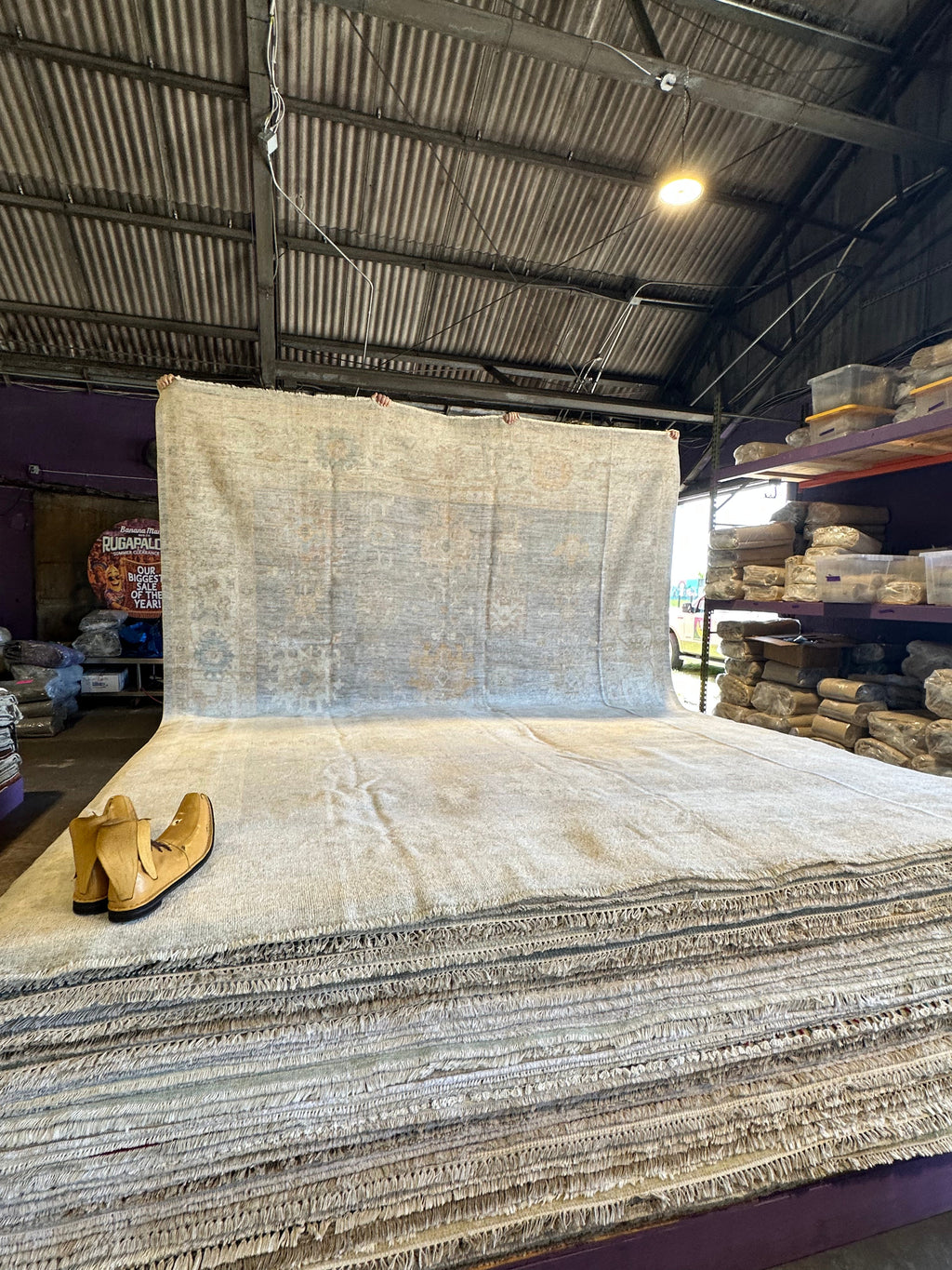 Large roll of carpet in a warehouse setting with a pair of boots on top.
