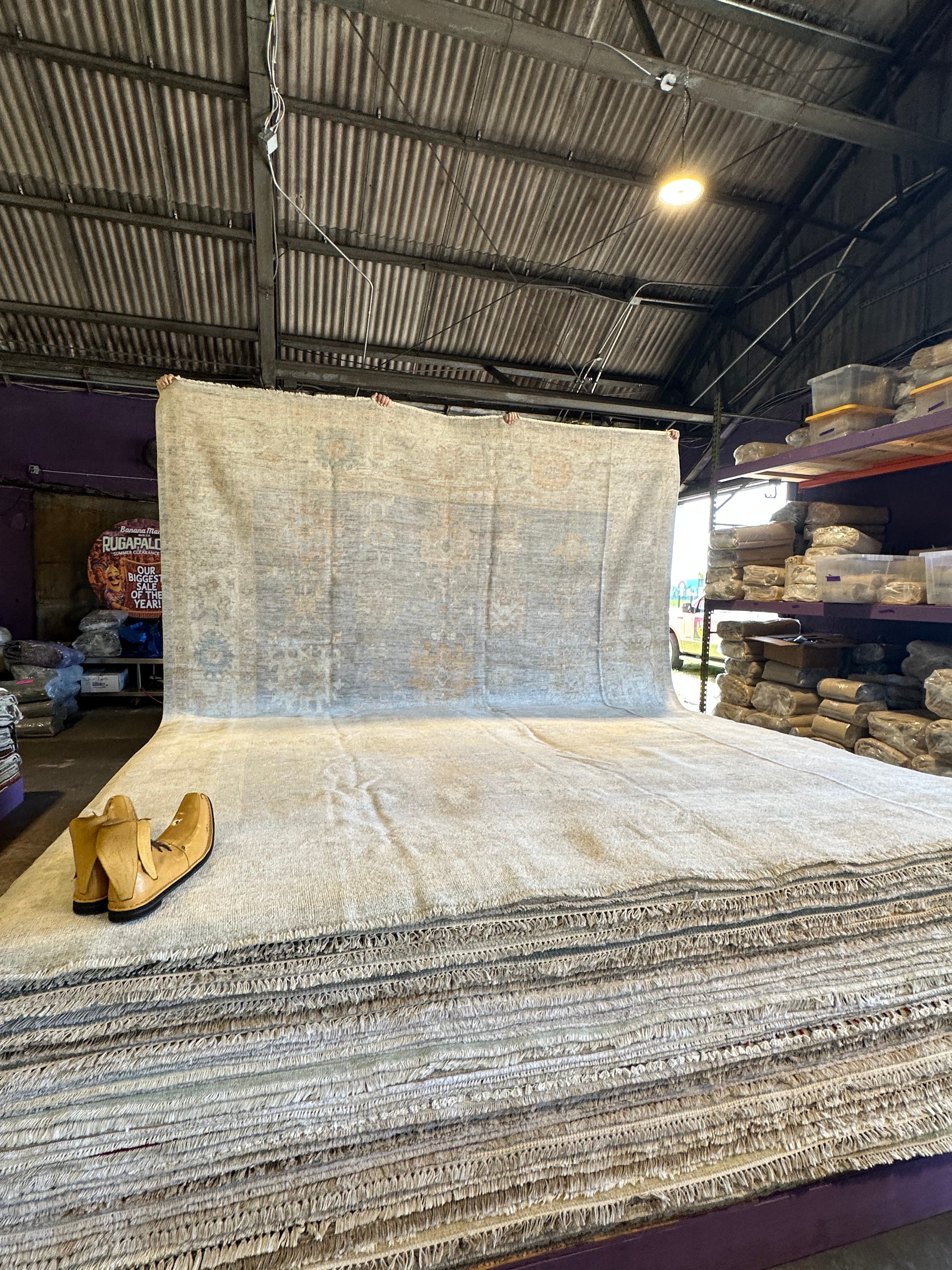 Large roll of carpet in a warehouse setting with a pair of boots on top.