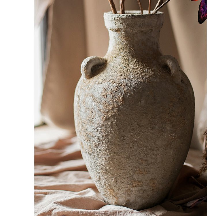 Textured ceramic vase with handles on a soft fabric background