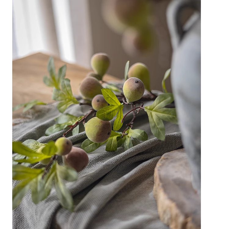 Decorative branch with fruits and leaves on a textured surface