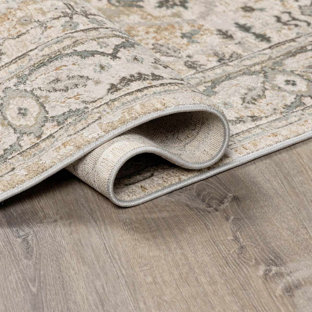 Patterned rug being rolled out on a wooden floor