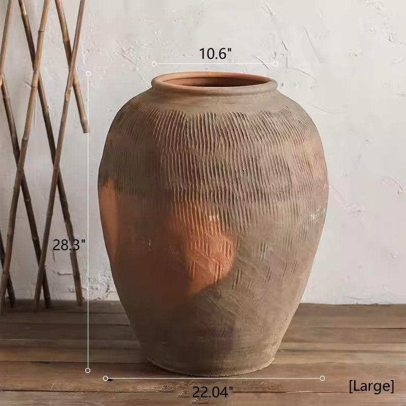 Large terracotta vase with measurements on a wooden surface and white wall background