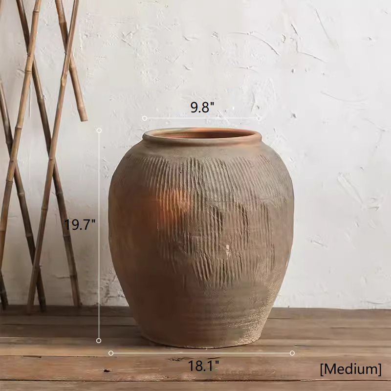 Terracotta pot with measurements on a wooden surface against a white wall.