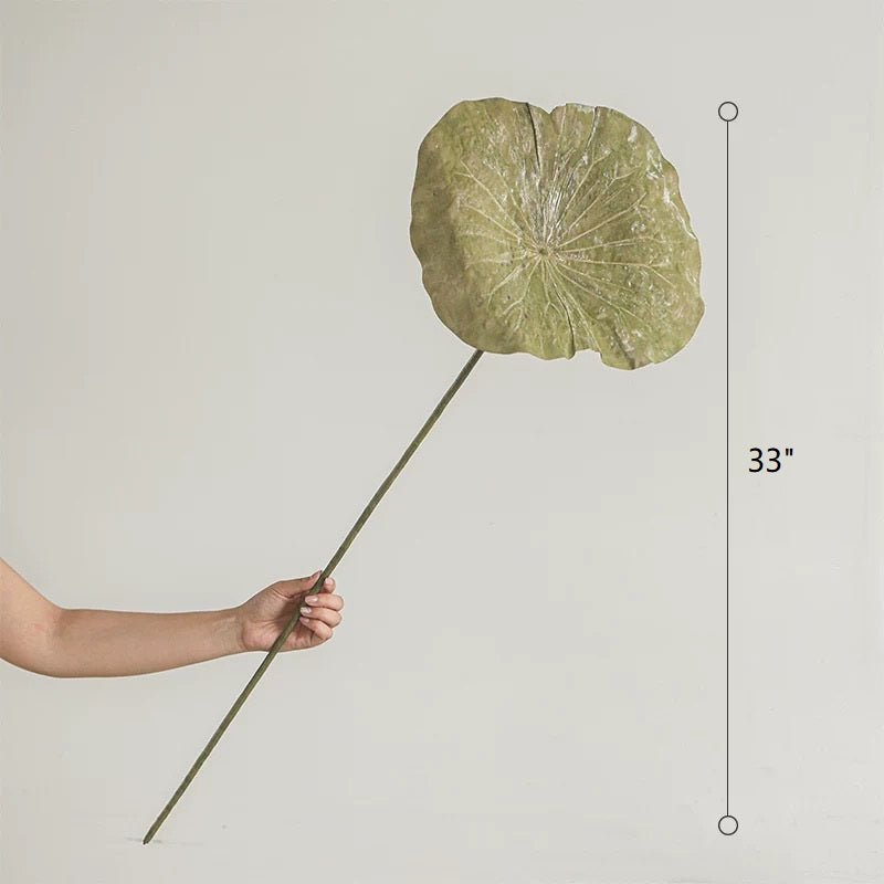 Hand holding a large decorative leaf with measurement label on a plain background