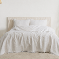 Minimal neutral bedroom featuring soft linen bedding, layered cream pillows, and warm natural textures in a quiet luxury European-inspired space. | Sorelle Rossi Shoppe